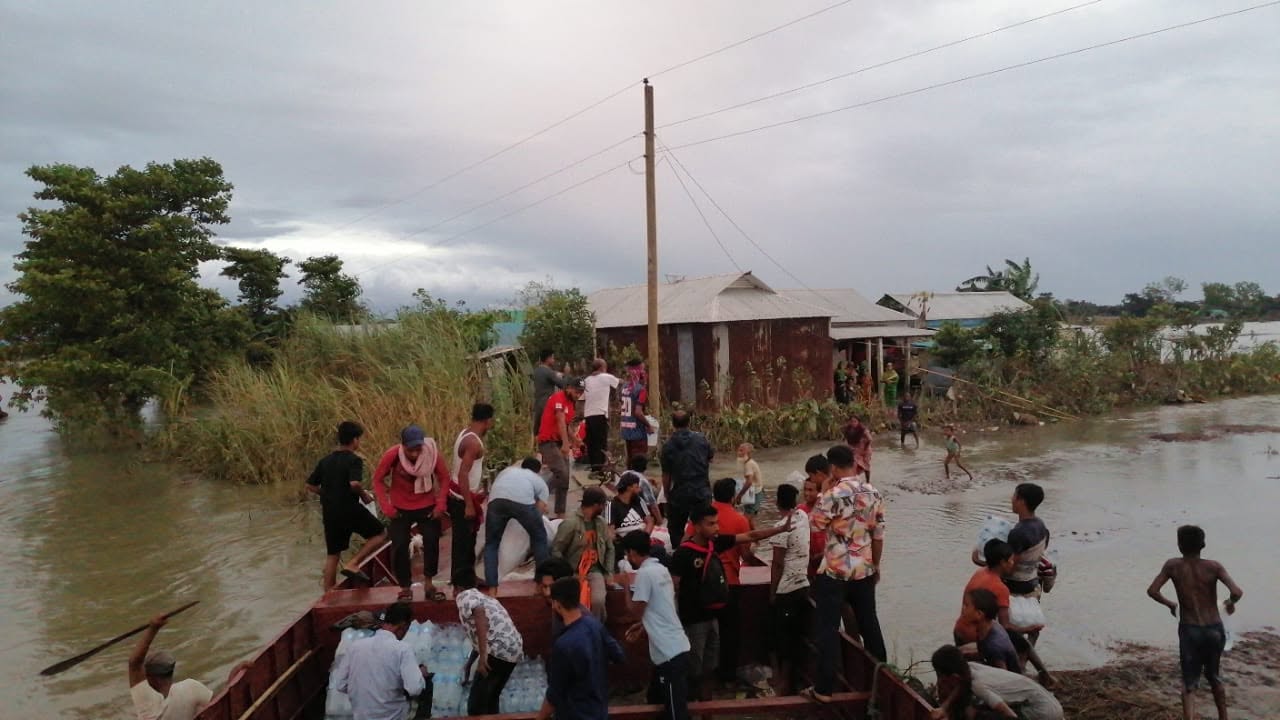 Volunteers unloading a relief boat beside flooded homes in Bangladesh