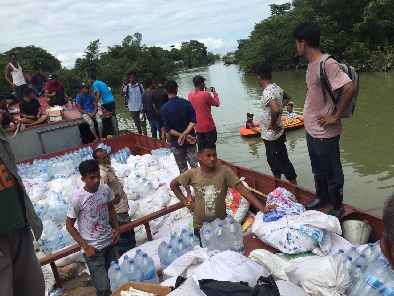 Volunteers on a boat loaded with drinking water and sacks of food during a flood in Bangladesh