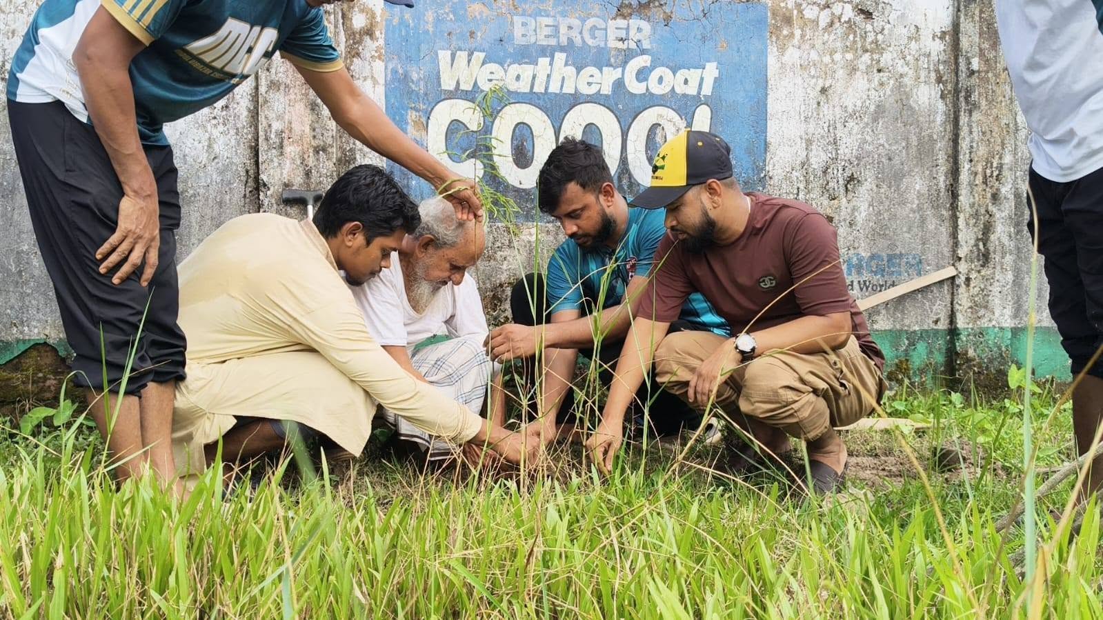 Volunteers and an elderly villager planting a sapling together