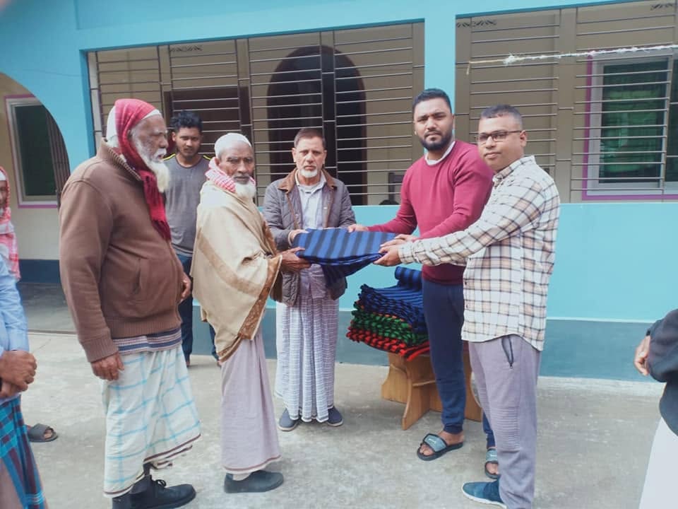 Warm blankets being handed to older men in a village